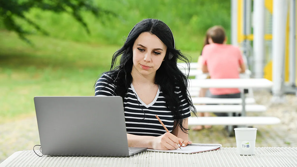 Projektbild - Frau mit Laptop am Tisch, draußen