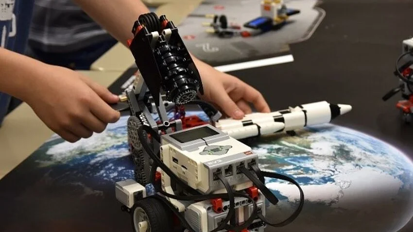 Kinderhände mit Bauteil von Lego-Technik