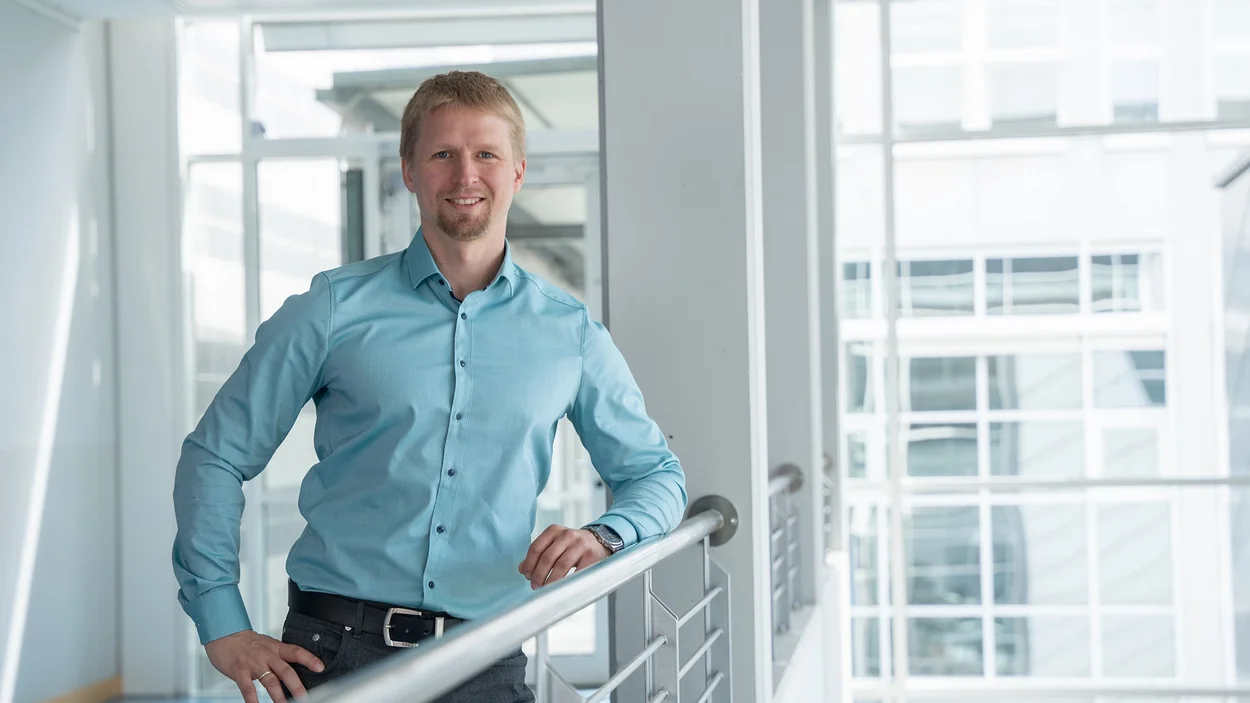 Professor Florian Wasser steht in blauem Hemd am Geländer