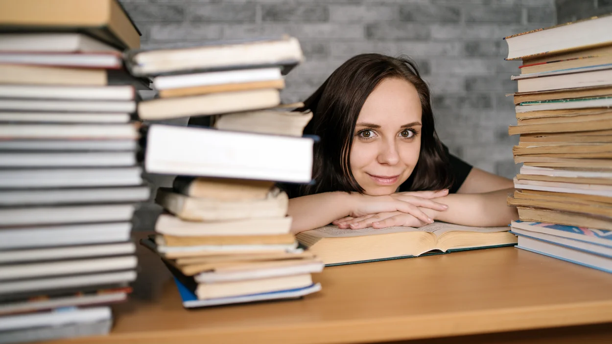 Projektbild - Schreibtisch mit Bücherberg und Frau