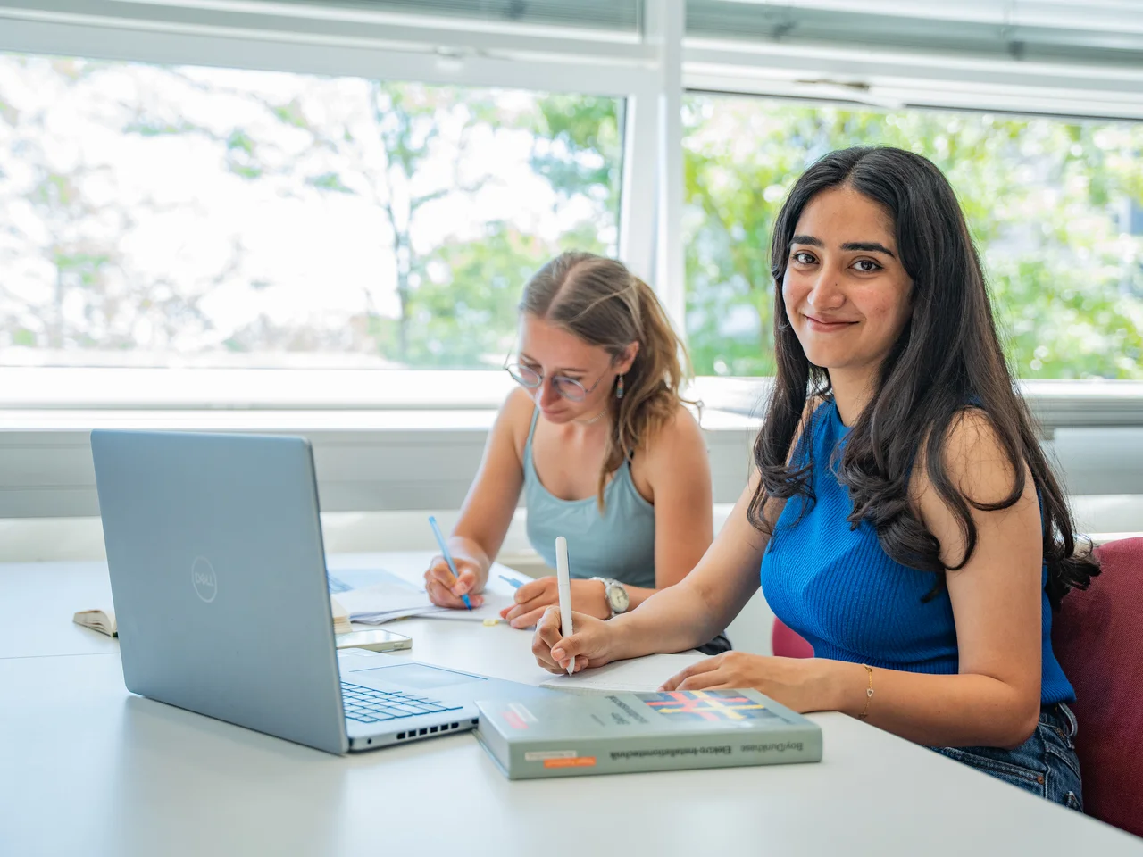 Zwei Studentinnen recherchieren in der Bibliothek nach Nebenjobs.
