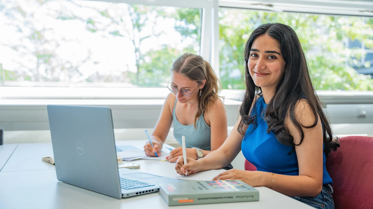 Zwei Studentinnen recherchieren in der Bibliothek nach Nebenjobs.