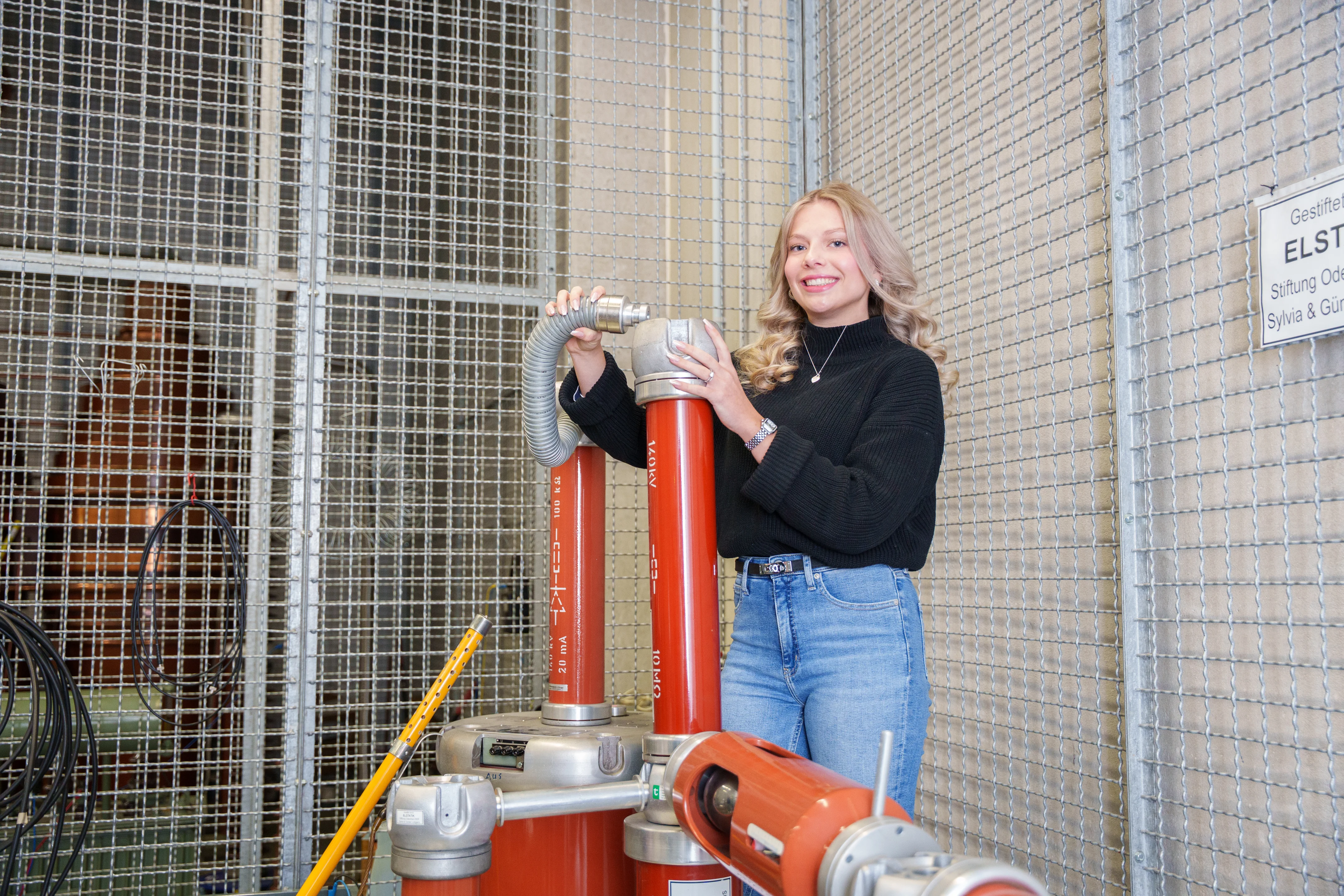 Eine Studentin in einem Labor mit Hochspannungsausrüstung
