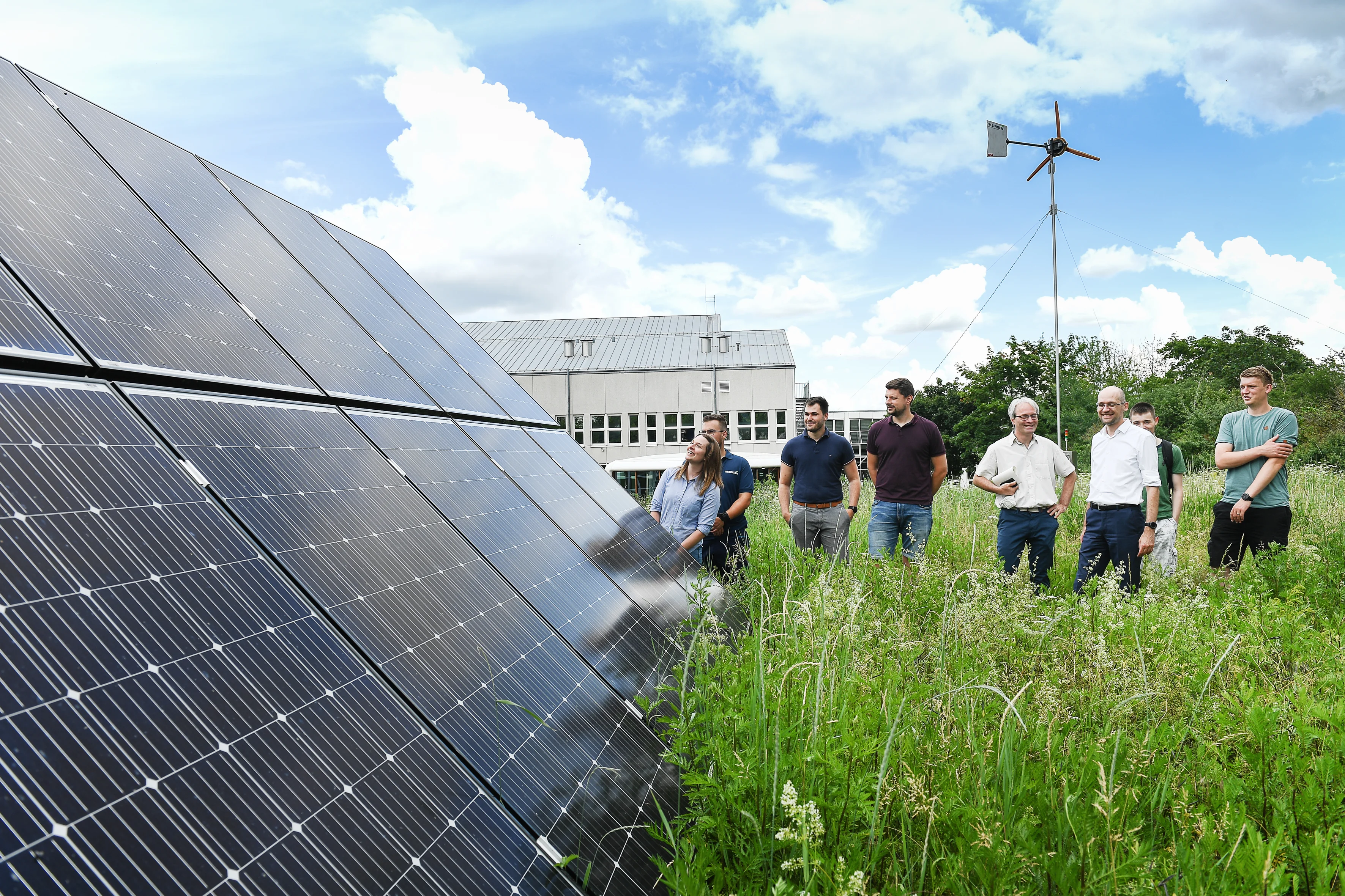 Das Bild zeigt die Solarpanele der TH Bingen mit Studierenden, Promovierenden und Professorinnen und Professoren danebenstehend.